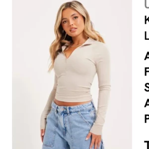 Greige långärmad polotopp med halv dragkedja - Säljer en greige långärmad polotopp med halv dragkedja framtill. Toppen har tight passform. Köpt från Nelly och knappast använd.