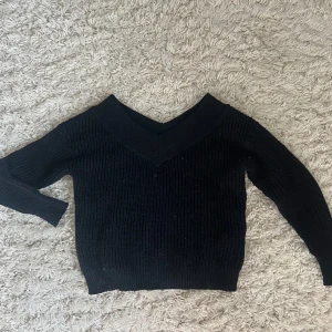 Svart stickad tröja med v-ringning från ONLY - Säljer en svart stickad tröja från ONLY med snygg v-ringning. Tröjan har lång ärm och är ribbstickad vilket ger en skön och flexibel passform. Perfekt att matcha med jeans eller kjol för en stilren look.