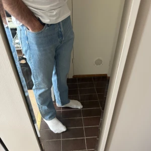 Ljusblå jeansbyxor herr - Klassiska ljusblå jeansbyxor med normal passform och rak siluett. Byxorna har fem fickor och stängs med dragkedja och knapp. Perfekta för en avslappnad stil och passar till det mesta.