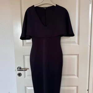 Marinblå långklänning  - Elegant marinblå långklänning från Missguided med djup v-ringning och cape-liknande ärmar. Klänningen har en figurnära passform och är perfekt för festliga tillfällen🩷 Om fler bilder önskas, skriv privat🩷Endast använd 1 gång  