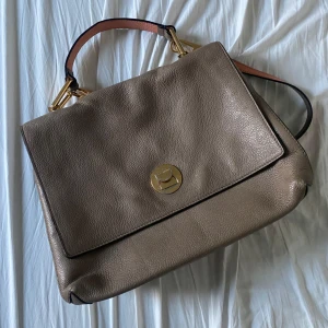 Coccinelle Väska - Äkta Coccinelleväska i skinn. Superbra skick, lite sliten i färgen på spännet. Kommer med axelrem. Medelstor. Pris går att diskutera!