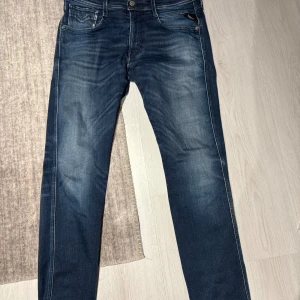 Blå jeansbyxor Replay Anbass herr W32 L32 - Säljer ett par klassiska blå jeansbyxor från Replay, modell Anbass. Byxorna har normal passform, raka ben och snygga slitningar framtill. Nypris 1799 : mitt pris 399 jätte bra skick bara hör av er vid frågor 🍾🍾