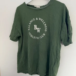 Grön t-shirt  - Grön t-shirt med vitt tryck på bröstet den är lite oversized