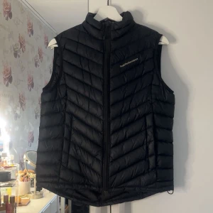 Svart dunväst från Peak Performance - Säljer en svart dunväst från Peak Performance, modell W Frost Down Vest. Västen har dragkedja framtill och en hög krage. Perfekt för dig som kanske vill va något varmare men inte en jacka💗