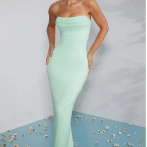 Mintgrön axelbandslös långklänning - Säljer en elegant mintgrön axelbandslös långklänning med figurnära passform. Klänningen har en stilren och enkel design som framhäver siluetten. Perfekt för speciella tillfällen när du vill sticka ut med en fräsch färg. Pris kan diskuteras.