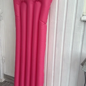 Uppblåsbar rosa badmadrass - Säljer en uppblåsbar badmadrass i stark rosa färg. Klassisk rektangulär form med upphöjda kanaler för extra komfort. Perfekt för lata dagar vid poolen eller stranden. Enkel att ta med och blåsa upp.