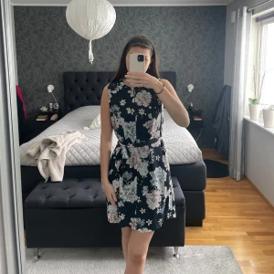 Blommig klänning - Blommig klänning från Stockholm i strl 40. Jättefint skick, medföljer ett skärp som kan knytas runt midjan exempelvis. OBS mindre i storleken då jag vakigtvis är S/XS