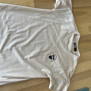 Karl Lagerfeld t shirt - Säljer en vit t-shirt från Karl Lagerfeld med en liten broderad Karl Lagerfeld-ikon på bröstet. T-shirten har rund hals och korta ärmar. Perfekt för en clean och stilren look.