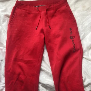 Ett röt sail racing sett - Hej säljer nu mitt röda sail racing sett eftersom det inte kommer till användning längre har används cirka 5 gånger och är i bra shick det ändå som är fel är att en av knapparna på ena sönder ramlat av men går lätt att byta ut och fixa, ett litet hål som sytts och fågra fläckar som går bort i tvätten! Settet är i storlek M men passar både S och XS. Pris kan också diskuteras, köpt från ord pris =  2500. Om man vill köpa separat så är byxorna 400 och tröjan 1000