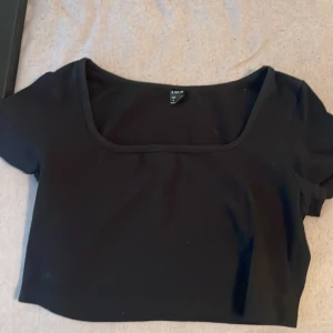 Svart croppad topp från Shein - En svart croppad topp från Shein med korta ärmar och rundad halsringning. Enkel och stilren design som passar till många olika outfits.