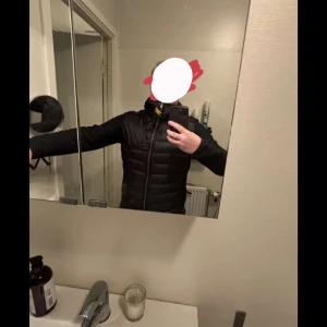 Svart pufferjacka från Parajumpers - Säljer en svart pufferjacka från Parajumpers med quiltade partier framtill och baktill. Jackan har dragkedja, hög krage och en gul detalj vid halsen. Perfekt för kyliga dagar och har en sportig look. Kvitto och tags medföljer såklart! Nypris på jackan 5000