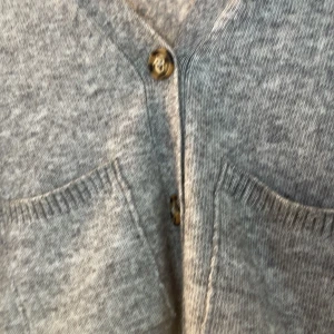 Kofta  - Mysig grå stickad kofta från Gina Tricot med två knappar framtill och fickor. Koftan har lång ärm och en något oversized passform, perfekt att slänga på sig över en topp. Enkel och stilren design. Har aldrig använt den, skriv vid mer bilder eller frågor💕