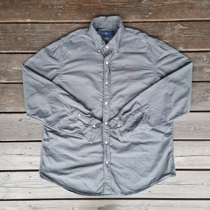Ralph lauren skjorta - 📊 Färg: Mörkgrön  📏 Storlek: Extra Large (XL)  📐 Mått: Längd - 84cm Axelbredd - 52cm  ♻️ En långärmad grå Ralph lauren skjorta i storlek XL. Det står att den är XXL men den är mer som XL. I väldigt bra skick, inga fläckar, hål eller defekter! Perfekt nu när det börjar bli varmare och sommaren kommer!☺️  👕 Material: 100% Bomull  #mensfashion #mensstyle #ralphlauren #classicstyle #buttondown #shirt #fashion #Vintage #Ralphlaurenskjorta
