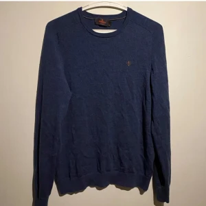 Blå merinoulltröja från Morris - Säljer en klassisk blå tröja från Morris i 100% merinoull. Tröjan har rund halsringning, långa ärmar och en liten broderad logga på bröstet. Perfekt för lager-på-lager och snygg till jeans. Tveka inte att skriva!