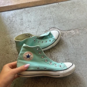 Turkosa Converse All Star sneakers - Säljer ett par klassiska Converse All Star sneakers i turkos färg. Skorna har högt skaft, vit gummisula och rund tå. Ikonisk Converse-logga på sidan och vita detaljer vid tån och sulan. Perfekta för en avslappnad och cool stil. Ings band.