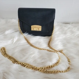  axelväska från Victoria's Secret med guldkedja - Snygg svart axelväska från Victoria's Secret med elegant guldfärgad kedja och låsdetalj framtill. 