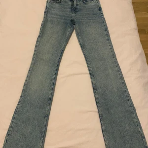 Blå bootcut jeans - Säljer ett par klassiska blå bootcut jeans med normal passform och hög midja. Jeansen har fem fickor och stängs med dragkedja och knapp. Perfekta till sneakers eller boots.