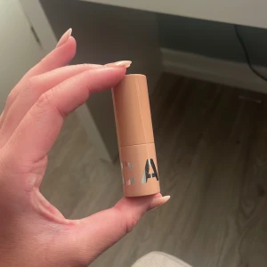 Läppstift CAIA - Säljer ett läppstift från CAIA i en snygg persikofärgad nyans. Hylsan är beige med silvriga detaljer och har en stilren design. Perfekt för att ge läpparna en fräsch och naturlig look.
