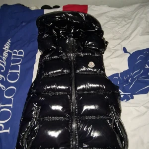 Svart glansig dunväst från Moncler - Säljer denna moncler väst för jag tyckte inte att den passar min stil den är nästan helt ny har använt 2-5 gånger, storlek 1