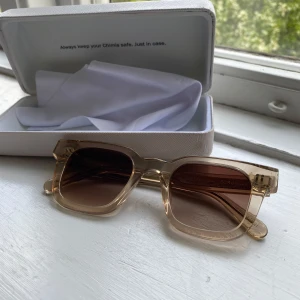 glasögon från Chimi - Snygga solglasögon från Chimi i en transparent beige färg med bruna tonade glas. Modellen har en fyrkantig form och tjock båge som ger en trendig look. Perfekta för soliga dagar och levereras med fodral och putsduk.