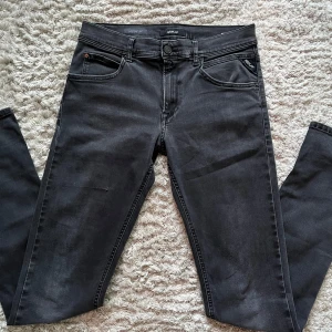 Replay jeans - Säljer nu ett par mörkgrå replay jeans i storlek 28/32. Jeansen har en snygg slimfit passform och har en klassisk framficks design. Dom har även en snygg slitning på ena knäet se bild 4. Dom är i modellen hyperflex så kan nog passa de flesta.