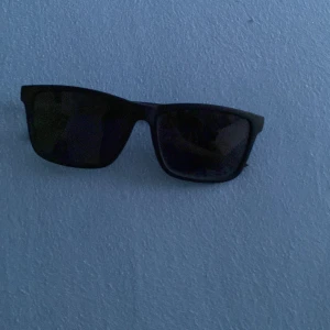 Svarta solglasögon med rektangulära bågar - Stilrena svarta solglasögon med rektangulära bågar och mörka linser. Perfekta för att ge en cool look och skydda ögonen mot solen. Passar dig som gillar klassisk och enkel design. Pris kan diskuteras