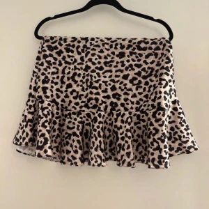 Leopardmönstrad volangkjol - Säljer en kort kjol med leopardmönster och volang nertill. Kjolen har en snygg och trendig look som passar perfekt till en cool outfit. Materialet känns mjukt och följsamt.