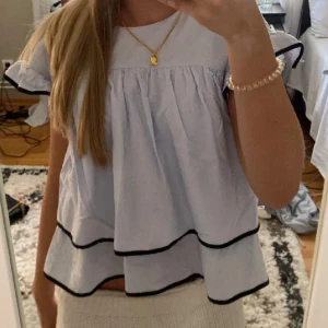 Ljusblå volangblus med svarta kanter - supersöt blå blus till sommaren. (Lånad bild)