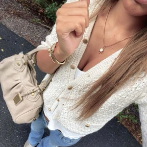 Beige stickad kofta med guldknappar - Superfin beige stickad kofta från H&M med snygga guldknappar och två fickor framtill. Koftan har en loose passform och är perfekt att slänga över en topp. Den är långärmad och har en mysig, chunky struktur som ger en trendig look.