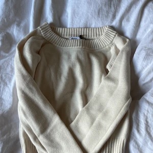 Beige stickad tröja från Subdued - Säljer en beige stickad tröja från Subdued med bred ribbad krage och muddar. Tröjan har en klassisk, enkel design och är långärmad. Perfekt för lager-på-lager och passar till många olika outfits.