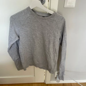 Grå sweatshirt från 157, storlek S - En basic grå sweatshirt från 157 i storlek S. Tröjan har rund halsringning, långa ärmar och är tillverkad i mjukt bomullsmaterial. Perfekt för en chill och avslappnad stil. Enkel och stilren design som funkar till det mesta.