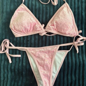 Rosa paljettbikini med snörning - Supersöt ljusrosa bikini med paljetter och snörning i sidorna. Triangeltopp med knyt i nacken och ryggen, samt matchande bikiniunderdel med knyt i sidorna. 