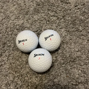 Begagnade Srixon bollar! - Bilderna visar tre vita golfbollar av märket Srixon med texten 'DISTANCE'. Det finns ingen bok synlig på bilderna, endast sportutrustning. Ingen information om författare eller titel kan utläsas.