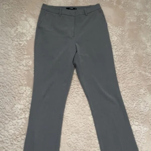 Gråa kostymbyxor från Bik Bok - Snygga grå kostymbyxor från Bik Bok i utsvängd modell. Byxorna är högmidjade och har hällor för bälte, fickor fram och bak samt stängs med dragkedja och knapp. Perfekta för en clean och stilren look. Materialet känns mjukt och följsamt. 