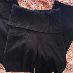 Svarta stickade yogabyxor  - Mysiga svarta yogabyxor med bred ribbad midja som kan vikas ner. Byxorna är stickade och har en loose passform, perfekta för chill dagar hemma. Materialet är mjukt och stretchigt för extra komfort. Tjockt material för kalla dagar och perfekt för vintern.