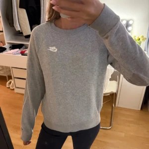 Grå sweatshirt från Nike - En stilren grå sweatshirt från Nike med klassisk rund hals och diskret Nike-logga broderad i vitt på bröstet.
