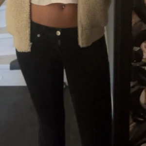 Svarta bootcut jeans low waisted  - Snygga svarta jeans med bootcut fit och low. Klassisk femficksmodell med knapp och dragkedja framtill. Perfekta till crop tops och hoodies för en clean look. Dom är slitna ner till men väldigt fina och basic 