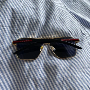 Svarta och guldiga solglasögon från Prada - Säljer ett par solglasögon från Prada. I mycket bra skick, smått använda men det syns inte. Inga repor.