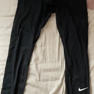 Svarta Nike leggings - Svarta leggings från Nike med klassisk vit swoosh-logga på benet. 🖤 Tight passform och stretchigt material som passar perfekt till träning eller chill. Snygga sömmar längs benen för extra stilpoäng. (MÅSTE HÄMTAS !) och jag vet inte om de är till för killar eller tjejer ! Köpte fel storlek ❤️