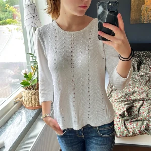 Vit stickad tröja med trekvartsärm - Säljer en vit stickad tröja med trekvartsärm och snyggt hålmönster. Tröjan har rund halsringning och är lätt och luftig, perfekt för vår och sommar. Passar till jeans eller kjol för en chill och stilren look.