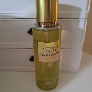 Victoria's Secret Bare Vanilla Sol mist - Fräsch och söt doftmist från Victoria's Secret i varianten Bare Vanilla Sol. Flaskan är genomskinlig med guldig kork och etikett, rymmer 250 ml. Doften har tydliga inslag av vanilj och soliga toner, perfekt för dig som gillar varma, mjuka dofter. Exakt som på bilderna. Svarar ej på förhandlingar.