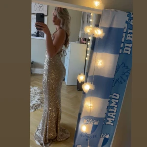 Glittrig balklänning 🌟 - Säljer min fantastiska balklänning. Klänningen har en tight passform, en slits framtill och snörning i ryggen. Den är endast använd två gånger. Klänningen släpar på mig som är 162cm lång. Den är köpt för 2500kr. Pris går att diskutera vid snabb affär💞