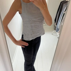 Ljusgrå linnetopp med knappar - Säljer en ljusgrå linnetopp i linne med öppen rygg som knäpps med knappar. Passformen är normal.