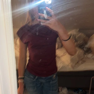 Vinröd topp från 157, storlek XS - Säljer en vinröd topp från 157 i storlek XS. Toppen har en enkel och stilren design med korta ärmar och rund halsringning. Materialet är mjukt och stretchigt, vilket gör den bekväm att bära. Perfekt att matcha med jeans eller kjol.