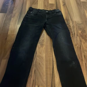 Svarta jeans från LAB Industries, stl 158 - Snygga svarta jeans från LAB Industries i regular fit med retro-vibe. Jeansen har klassisk femficksdesign, svarta sömmar och lätt tvättade detaljer på benen. Perfekta för dig som gillar en stilren look med lite edge.