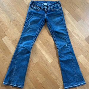 True Religion blå bootcut jeans - Snygga blå jeans från True Religion med bootcut passform och klassiska kontrastsömmar. Jeansen är lågmidjade och har bakfickor med detaljer. 