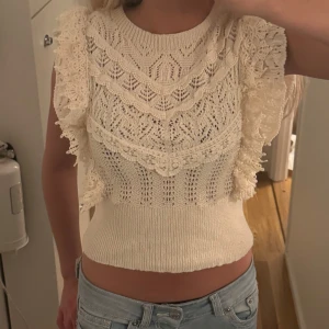Söt topp från Zara - Supersöt vit stickad topp med breda volangärmar och detaljerat spetsmönster. Toppen är croppad och har en tajt passform i midjan. Perfekt för dig som gillar romantisk och feminin stil. Snygg till både jeans och kjol!