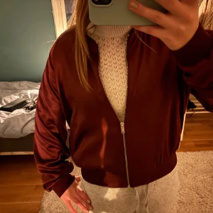 Mörkröd bomberjacka med dragkedja - Snygg mörkröd bomberjacka från monki som tyvärr inte kommer till användning. Jackan har ribbade muddar vid ärmslut och midja. Pris kan diskuteras vid snabb affär och postar snabbt!