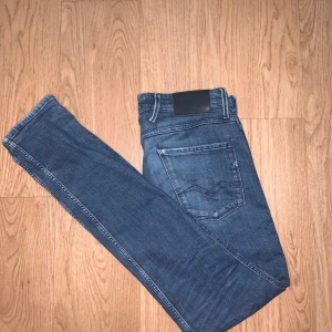 Replay Anbass slim jeans blå - Snygga blå Replay Anbass jeans i slim fit med klassisk femficksdesign och diskret logga på bakfickan. Jeansen har en mörk tvätt med lätt slitning och är tillverkade i mjukt jeansmaterial som sitter skönt och följer kroppen. Perfekta för dig som gillar stilrena och moderna jeans.