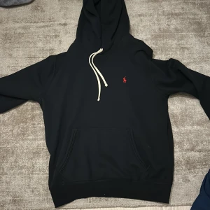 Svart hoodie från Polo Ralph Lauren - Svart hoodie från Polo Ralph Lauren. Perfekt för dig som gillar en stilren och enkel look. Jag säljer hoddien för att jag har vuxit ut den. Inte alls använt mycket. 
